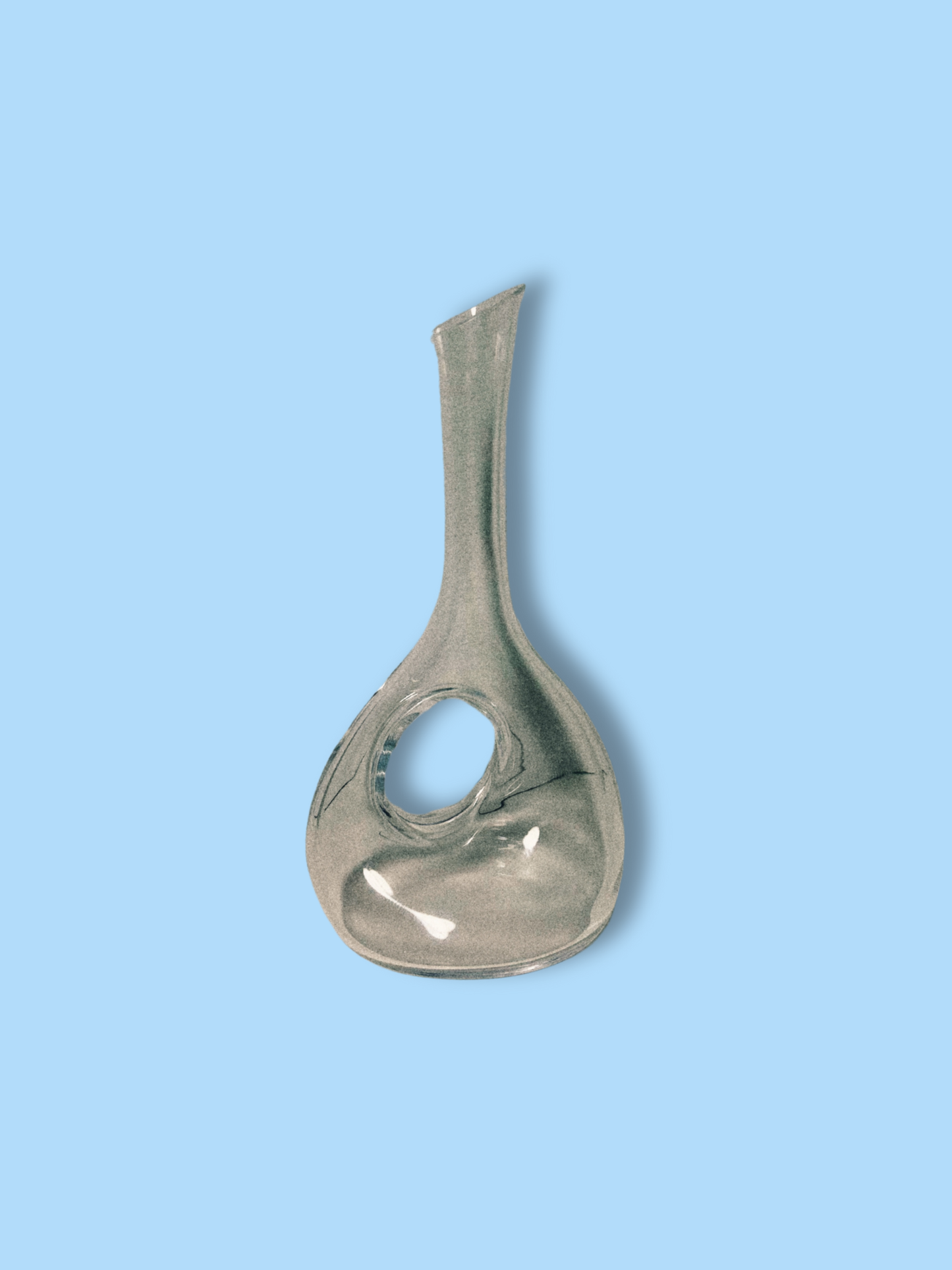 A clear crystal round wine decanter against a blue background.