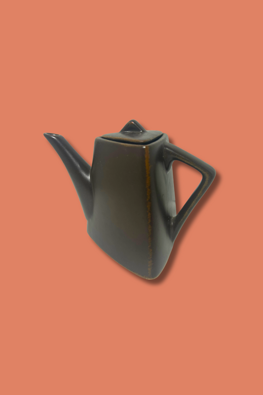 Black ceramic teapot on a peach background