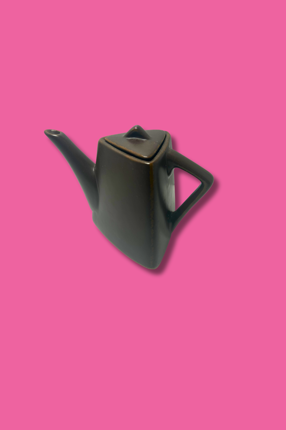 Black ceramic teapot on a pink background