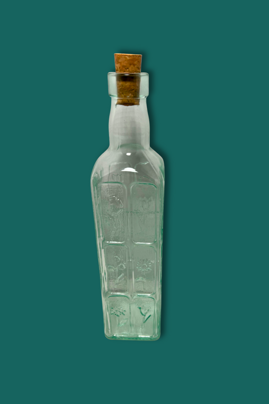 Clear glass bottle with a cork on a green background