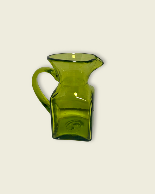 Green glass pitcher on a beige background