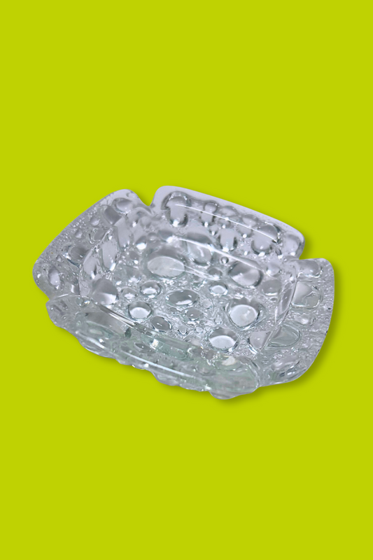 Clear glass ashtray on a green background