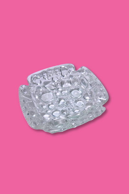 Clear glass candy dish on a pink background