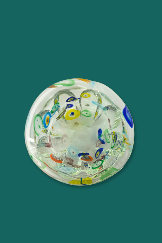 Decorative glass bowl with multicolored designs on a green background