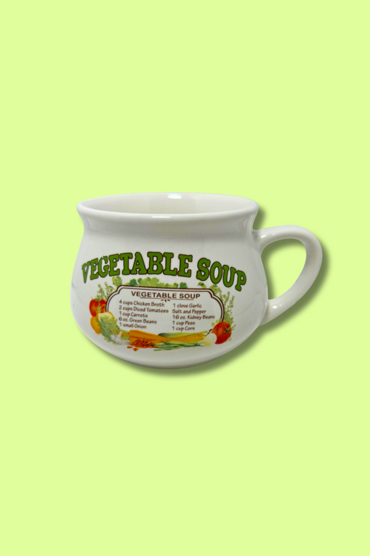 White ceramic mug with 'Vegetable Soup' text and graphics on a light green background