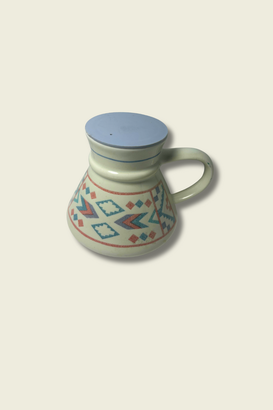 Ceramic mug with geometric pattern and blue lid on a beige background