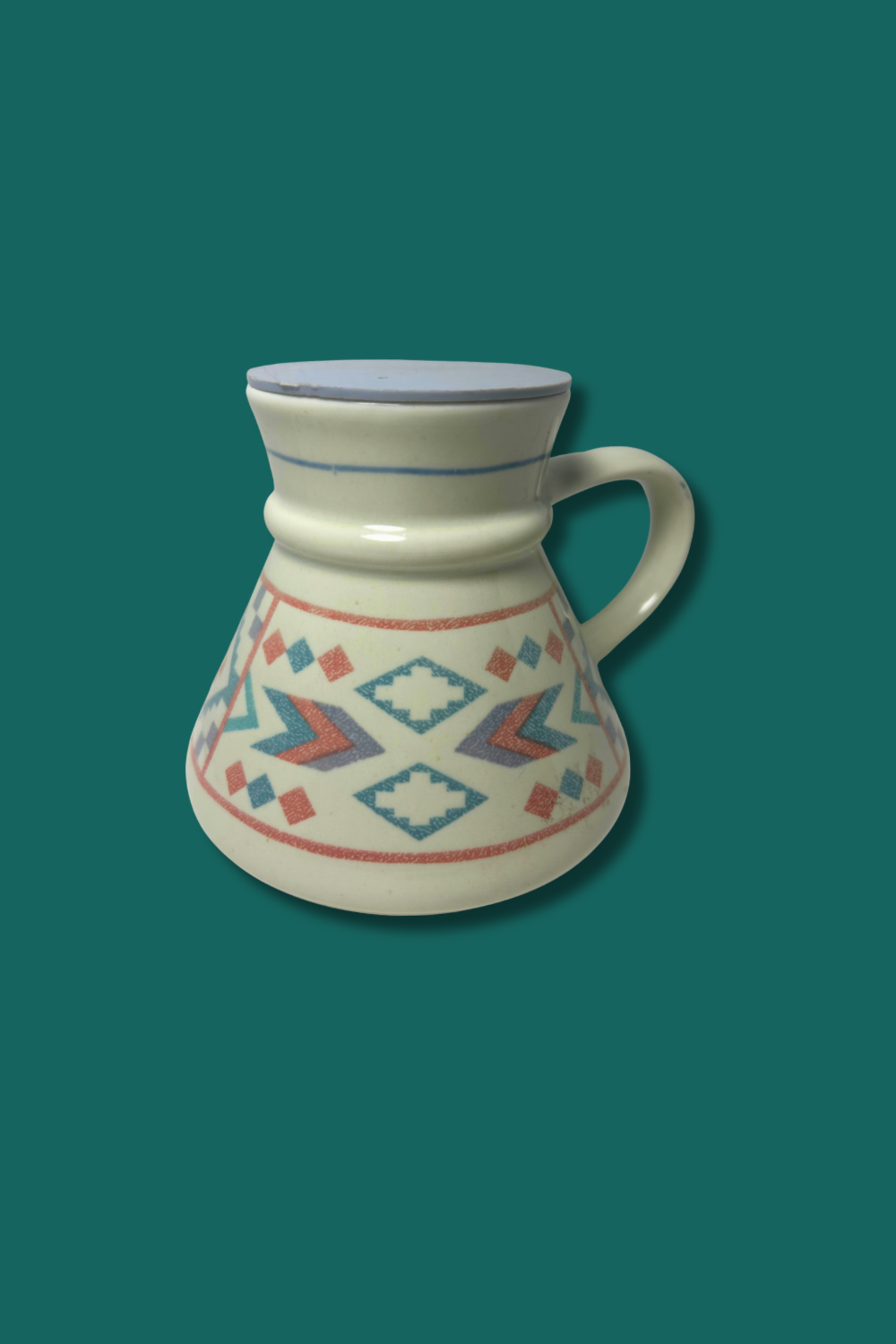 Ceramic pitcher with geometric patterns on a teal background