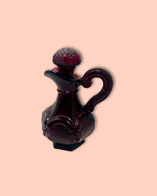 Dark red glass cruet with textured design on a beige background