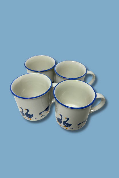 Four ceramic mugs with blue rims and decorative elements on a light blue background