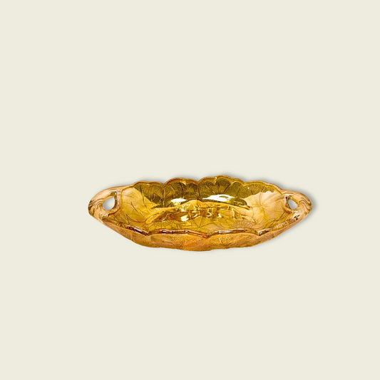 A vintage marigold Indiana carnival glass relish dish against a beige background.