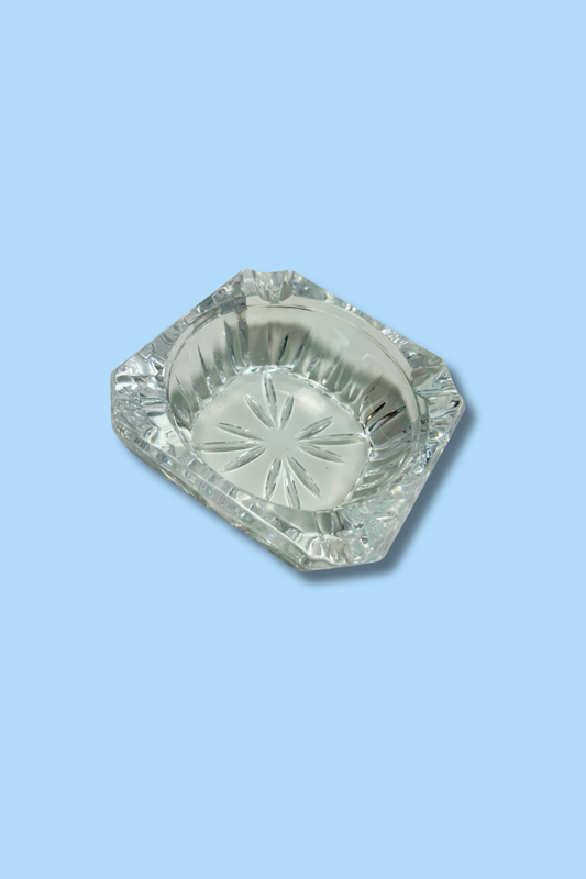 Clear glass ashtray on a light blue background