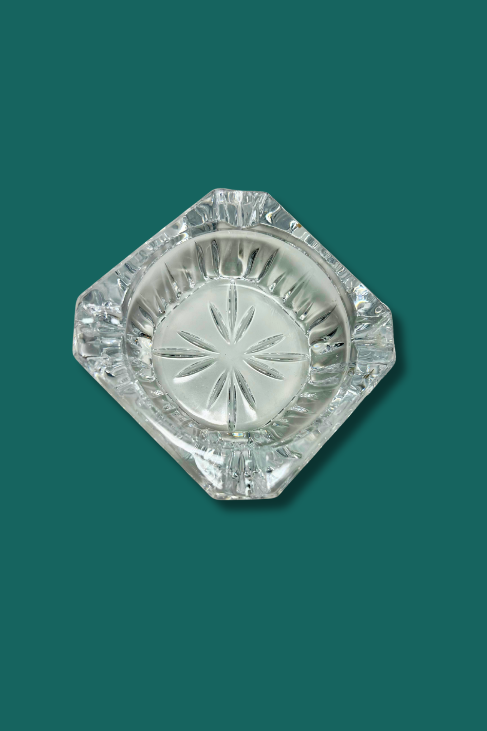 Clear crystal ashtray with star design on a green background