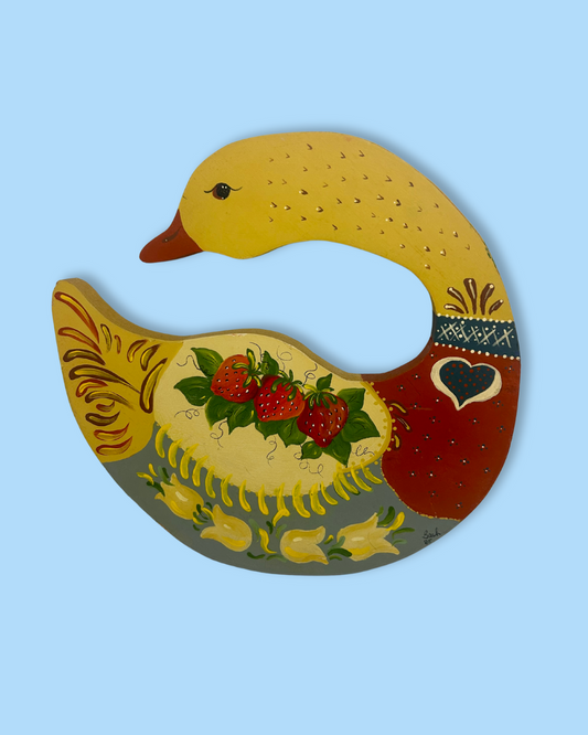 Decorative duck-shaped object with floral and strawberry design on a light blue background