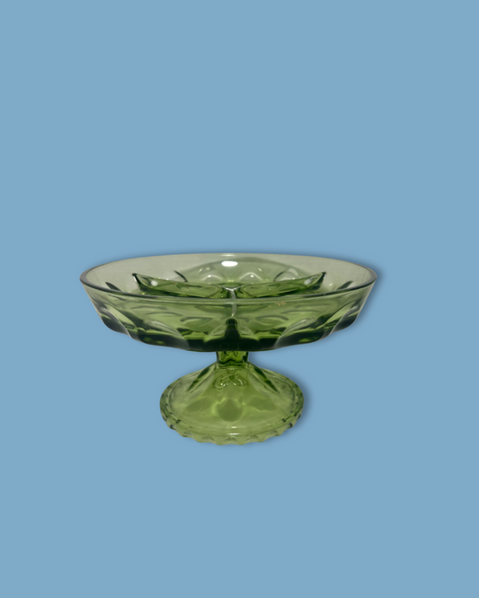 Green glass footed bowl on a blue background