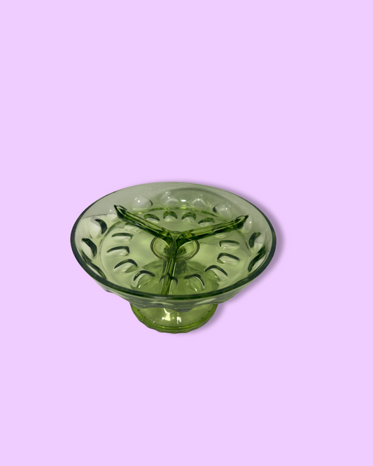 Green glass candle holder on a pink background