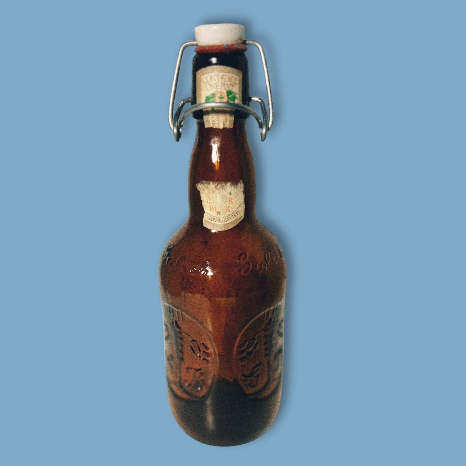 A vintage Grolsch beer bottle with a brown tint and decorative patterns, featuring a white cap and a label that partially shows the brand name.