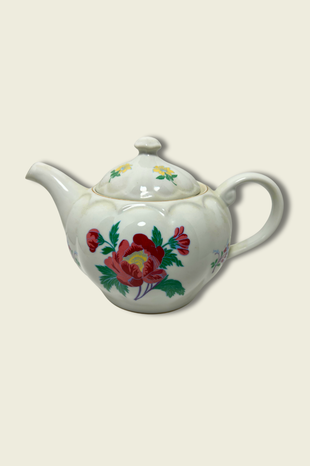 White teapot with floral designs on a beige background