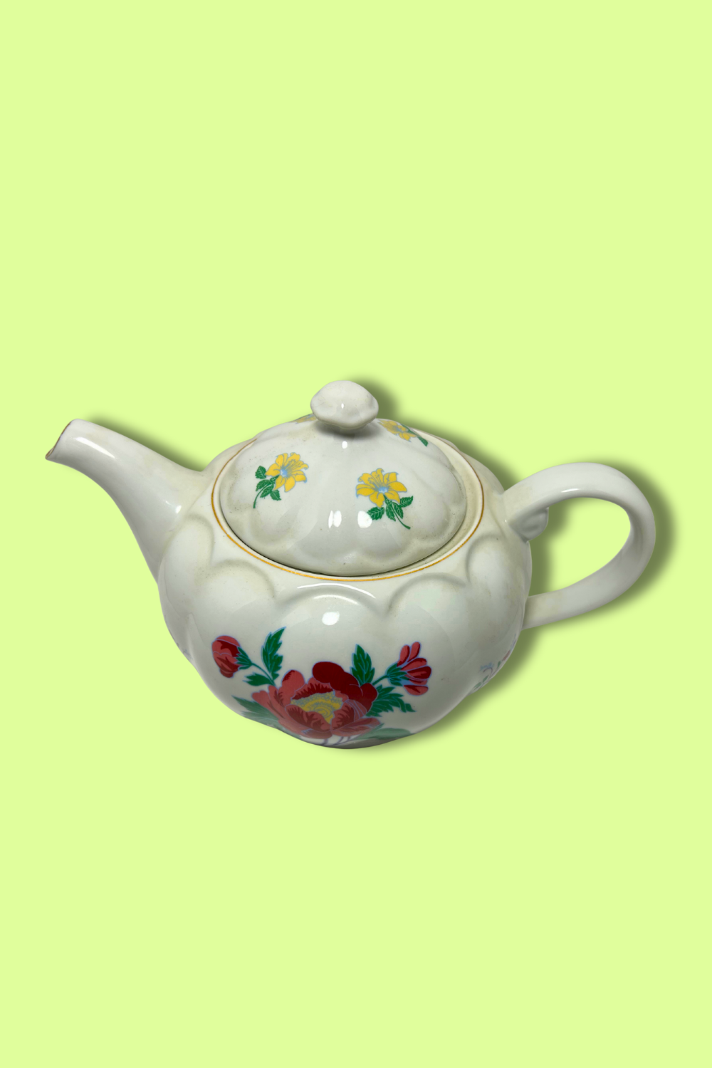 White teapot with floral designs on a light green background