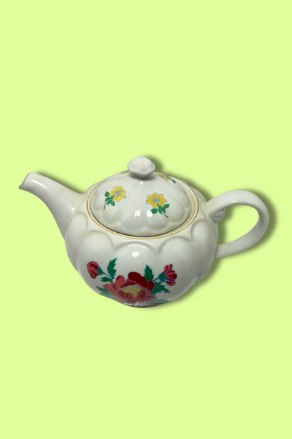 White teapot with floral designs on a light green background