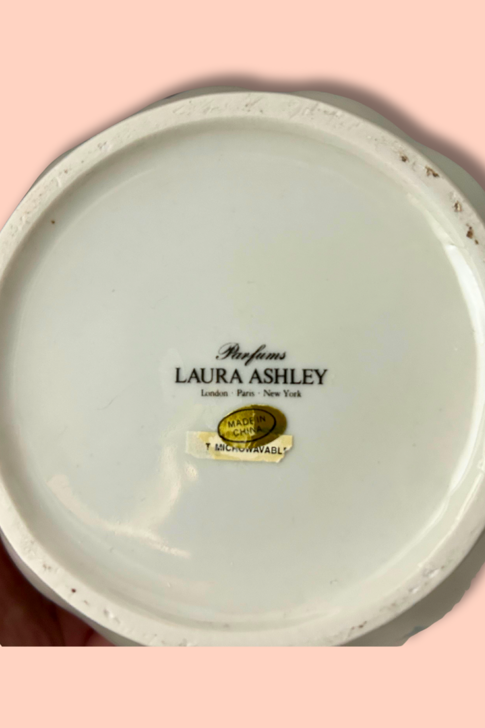 Round container with 'Laura Ashley' branding on a pink background
