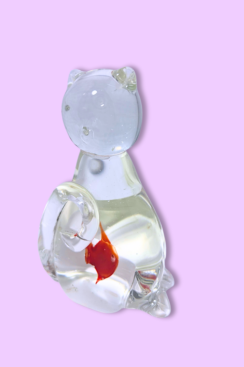 Glass sculpture of a cat with a red heart on a pink background