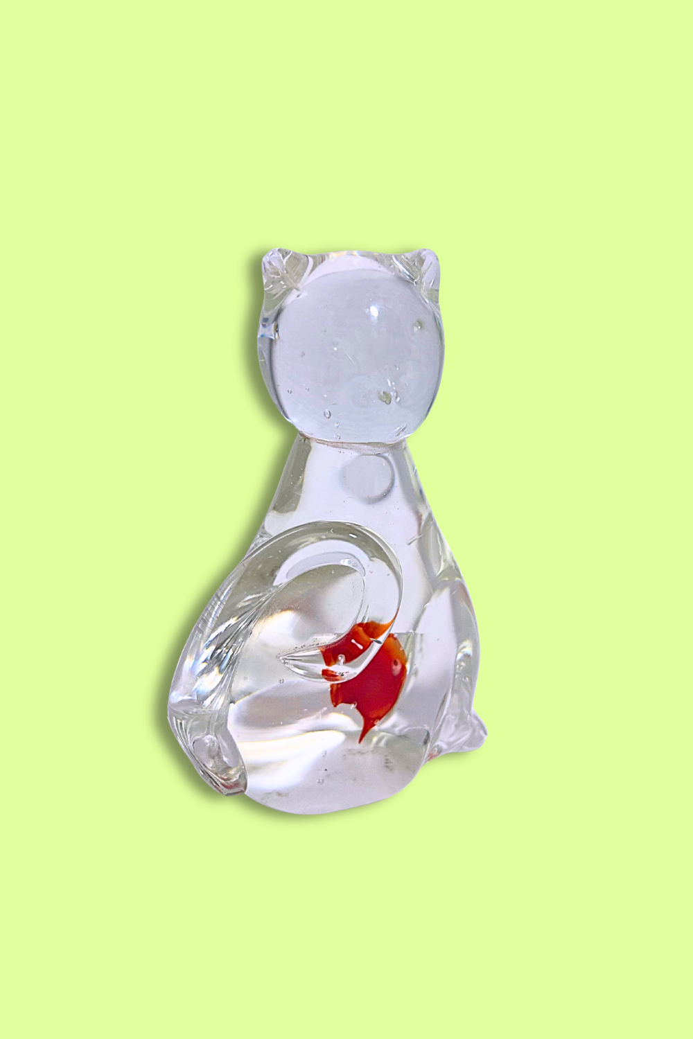 Glass fish bowl shaped like a cat with a goldfish on a light green background