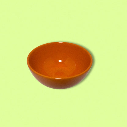 photo of vintage orange bowl on green background. 