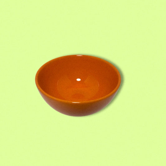 photo of vintage orange bowl on green background. 