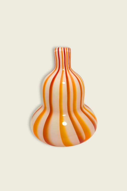 Glass vase with orange and white stripes on a beige background
