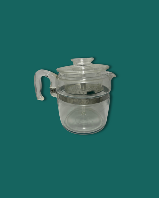 Clear glass teapot with silver rim on a green background