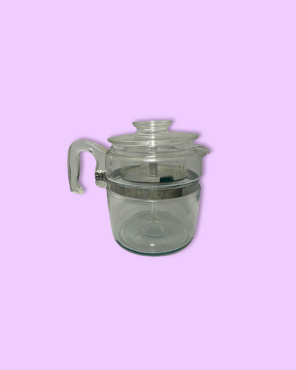 Clear glass teapot with a lid on a pink background
