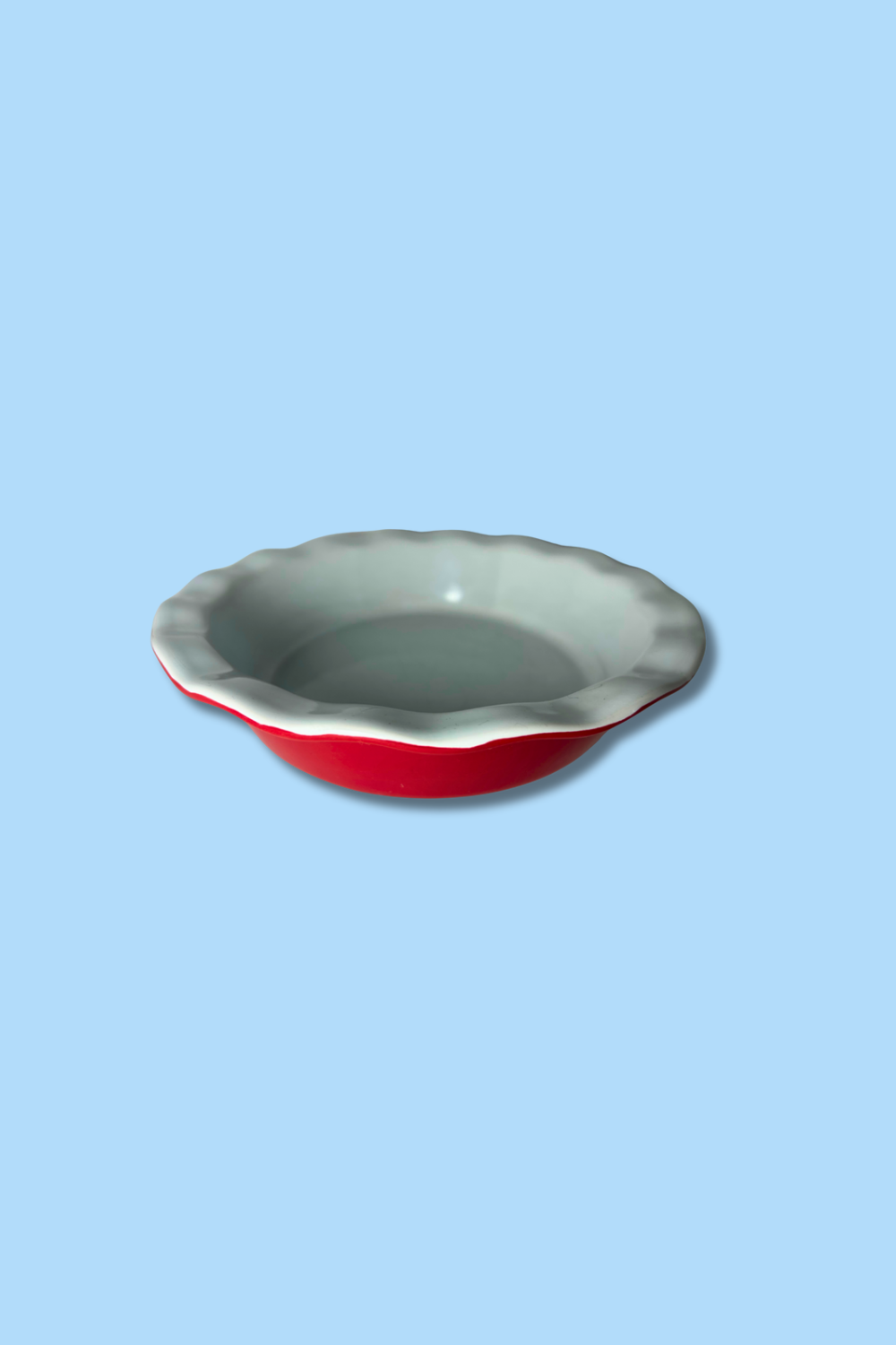 Pie dish with red interior and gray exterior on a light blue background