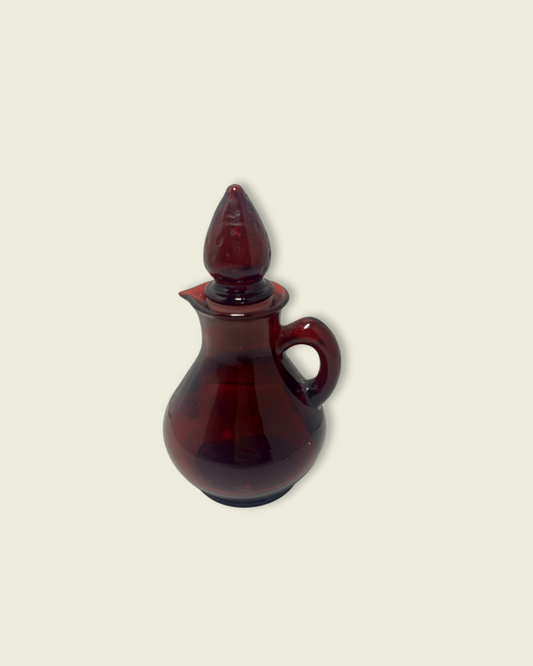 Red glass cruet with a stopper on a beige background
