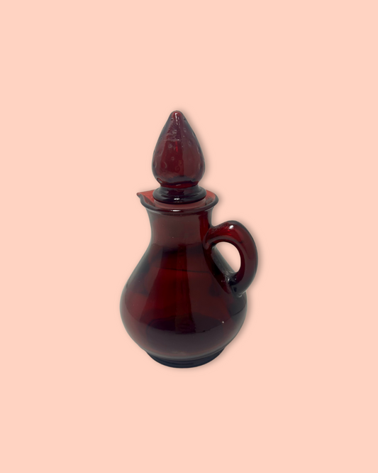 Red glass cruet with a stopper on a beige background