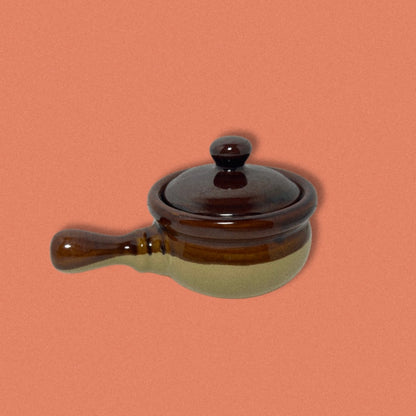 A brown and beige vintage stoneware French onion soup bowl with a lid and handle.