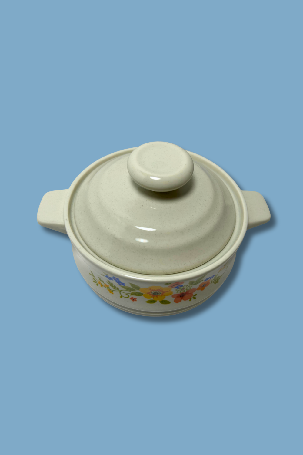 Ceramic casserole dish with floral patterns on a blue background