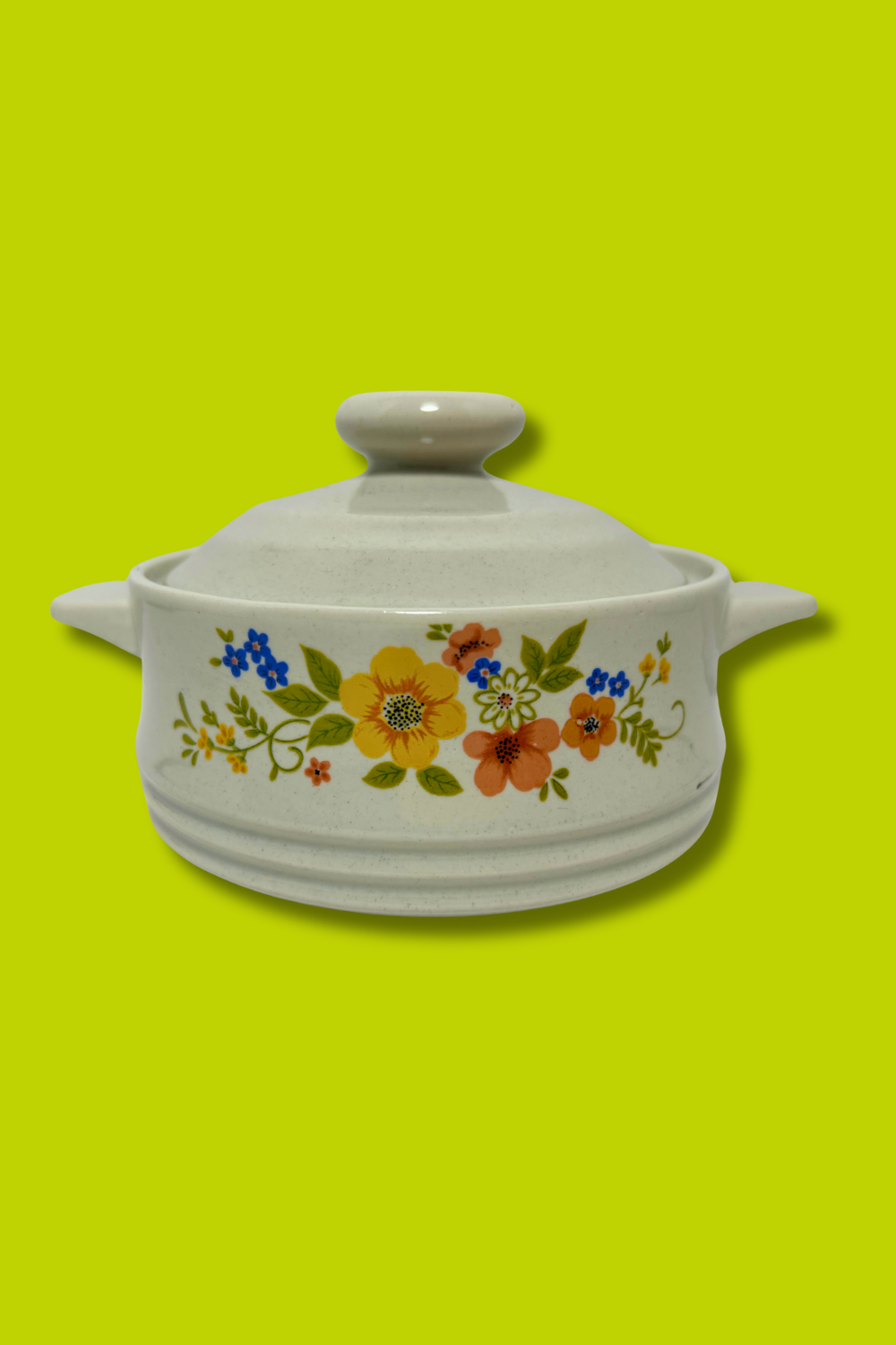 White ceramic casserole dish with floral patterns on a green background
