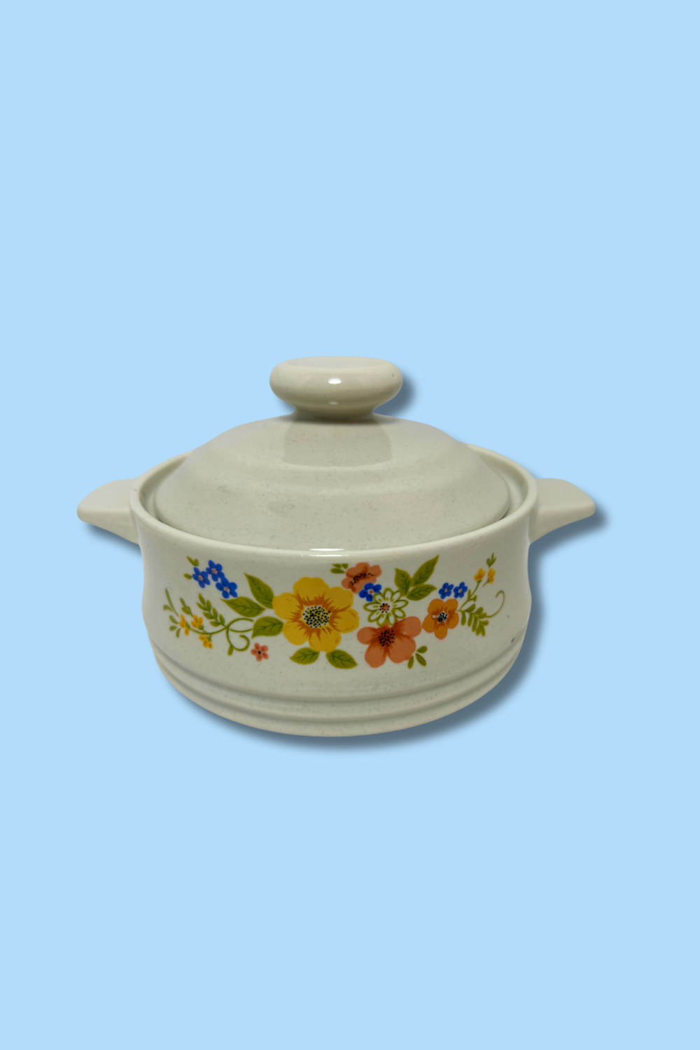 Ceramic casserole dish with floral design on a light blue background