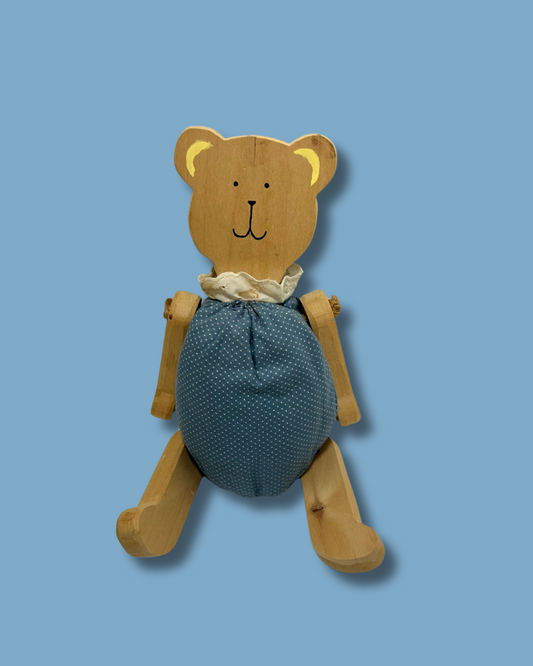Wooden teddy bear with a blue textured body on a light blue background