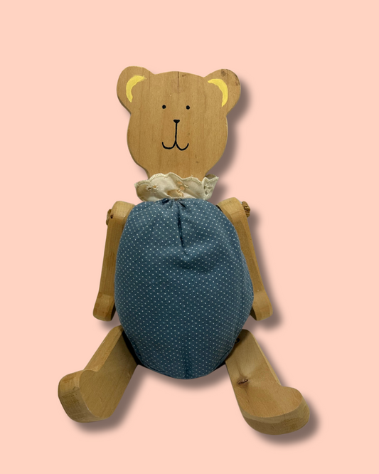 Wooden teddy bear with a blue polka dot body on a pink background