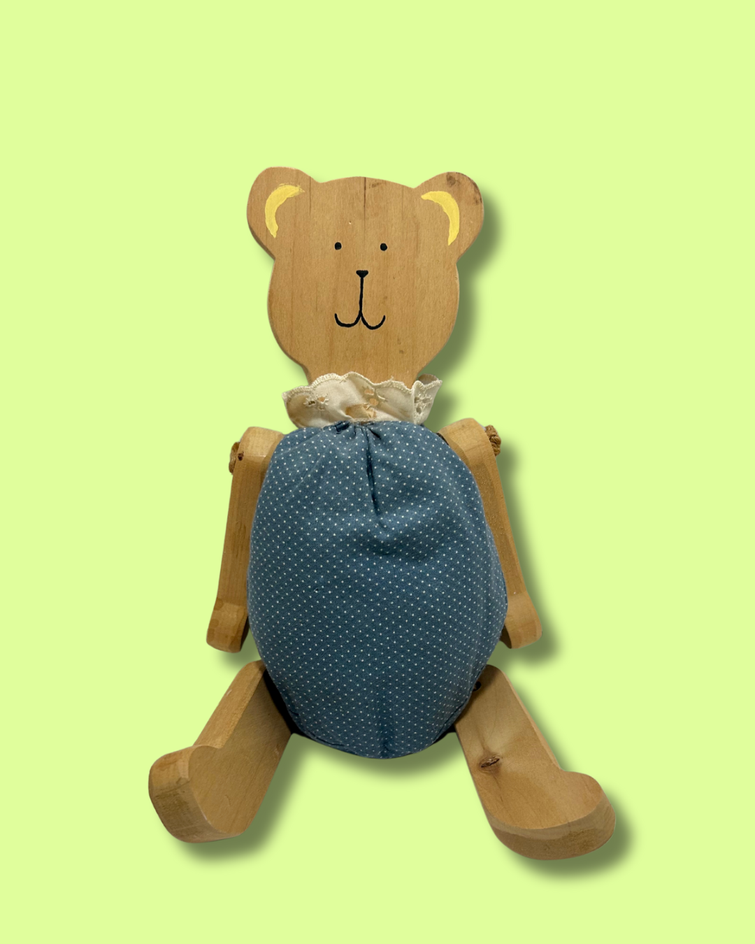 Wooden bear toy with a blue polka dot body on a light green background