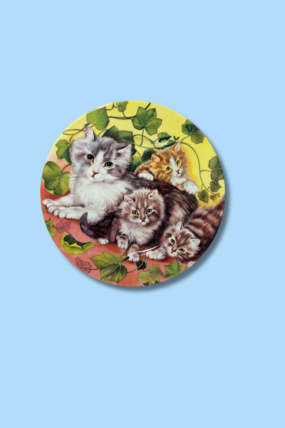 Round coaster with vintage-style illustration of kittens on a blue background