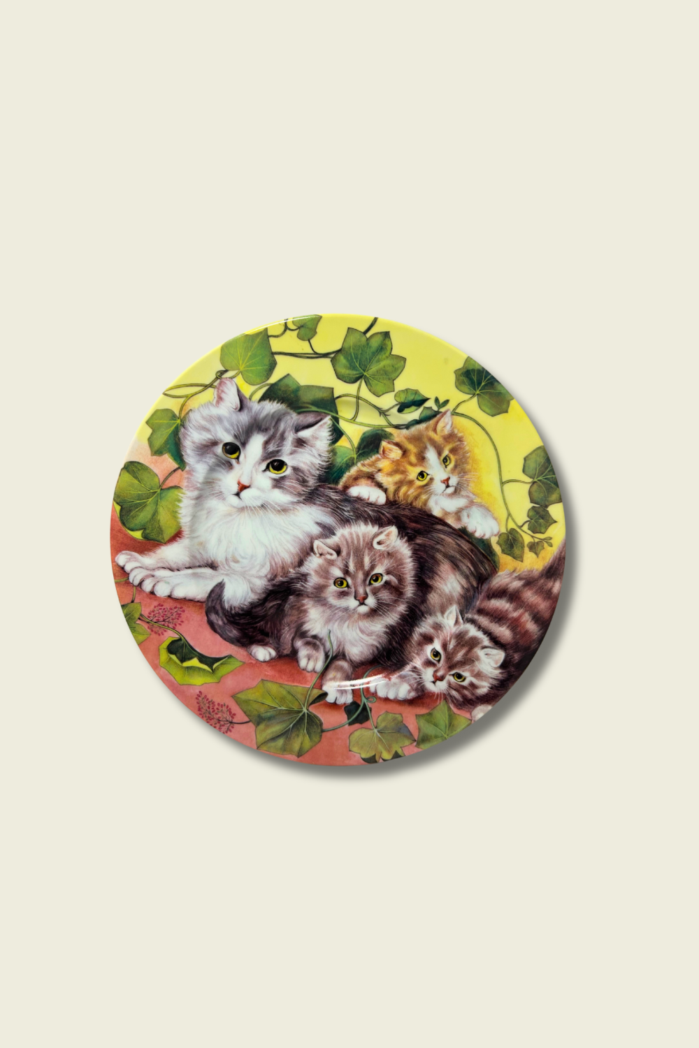 Circular illustration of kittens on a decorative plate with a floral background.