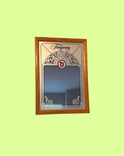 A vintage Tanqueray branded mirror with a decorative wooden frame